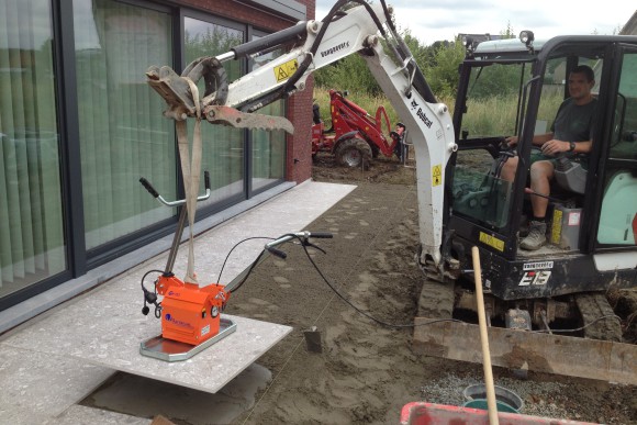 aanleg van terras in grote tegels met tegelzuiger